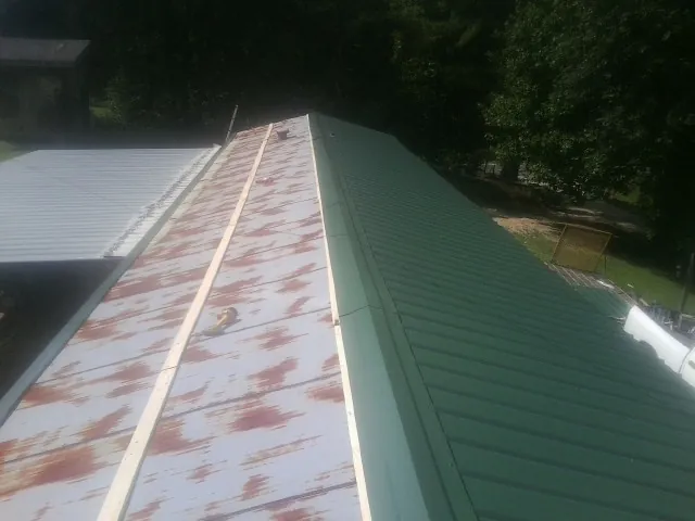 Old rusted panels beside newly installed green metal roofing — Wind Damage Roof Repair by Roofing Brothers in Melrose Park
