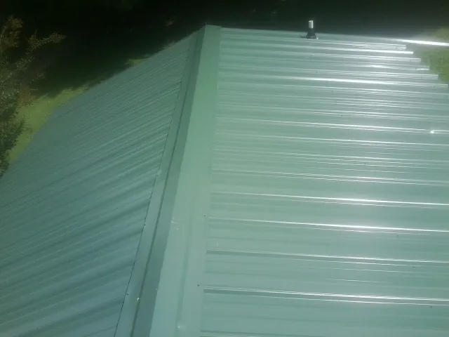 New green metal panels meeting at the ridge of a roof — Flat Roof Repair work by our crew in Melrose Park