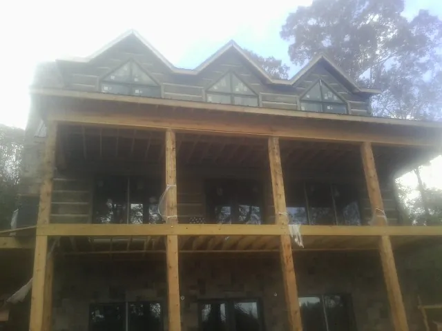 Dormers and porch framing on a large log home under construction — Roof Coating work by our crew in Melrose Park