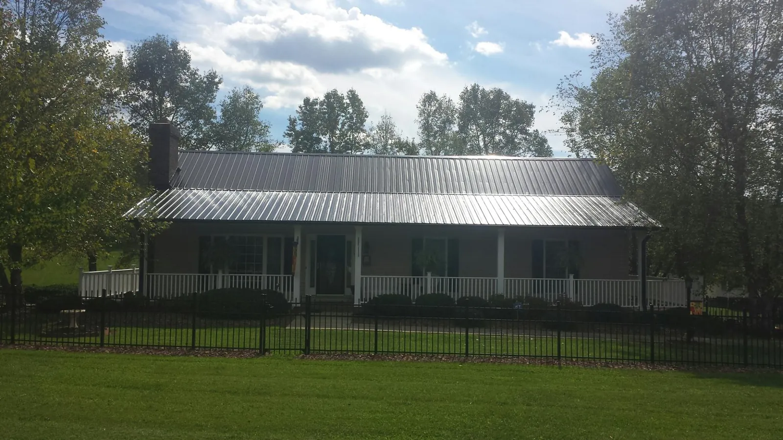 Gray metal roof on a brick ranch with a full width front porch — Gutter Guard Installation work by our crew in Melrose Park