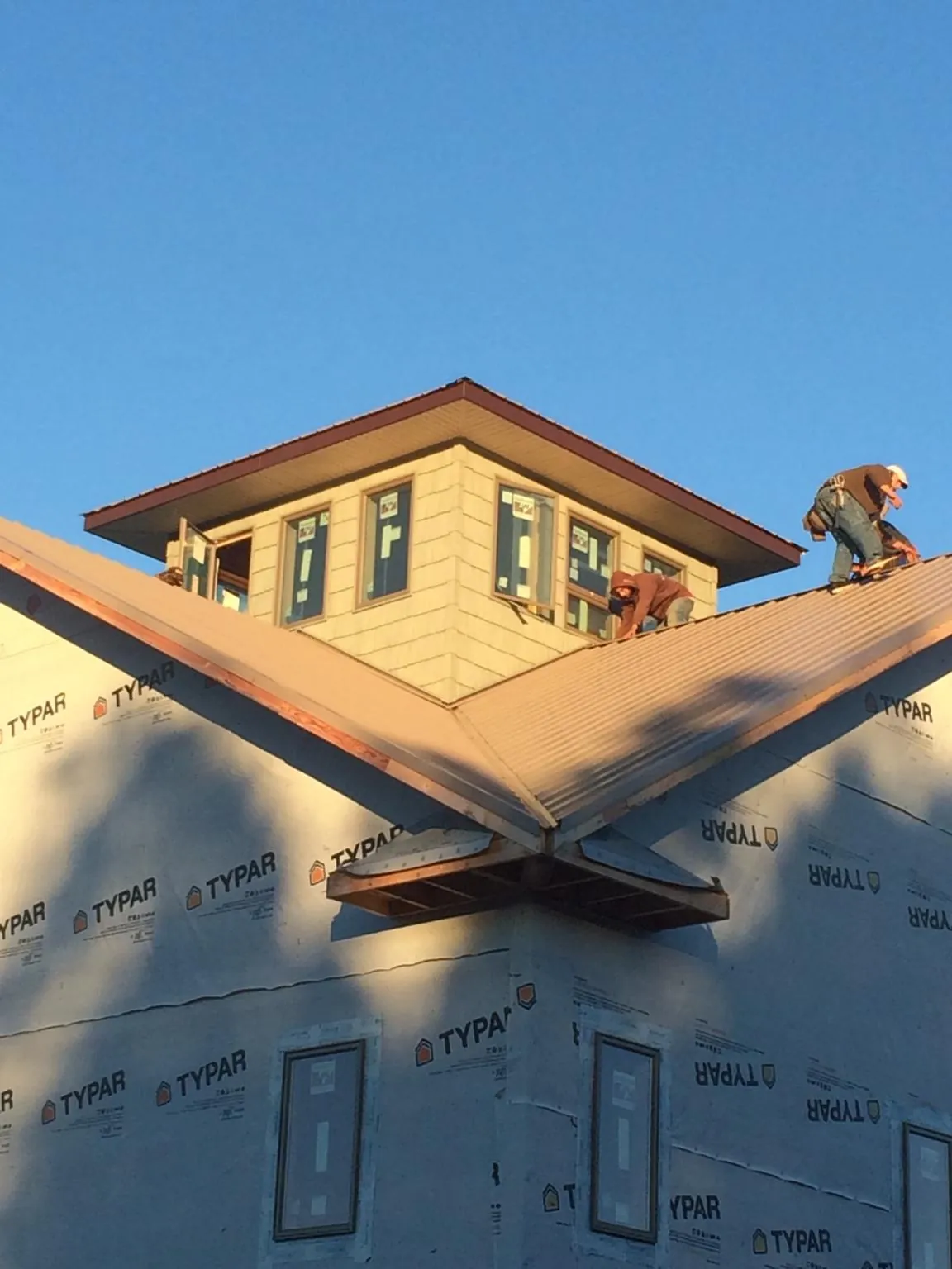 Roofers working around a rooftop cupola on a new metal roof at sunset — Roof Waterproofing in Melrose Park by Roofing Brothers